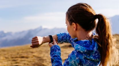 A runner looks at her fitness tracker 