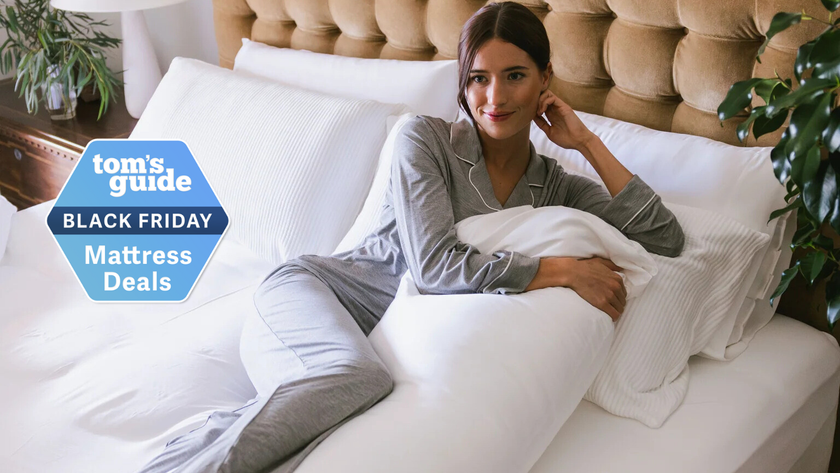 Woman holding the Cozy Earth Body Pillow in bed with TG Black Friday mattress deals badge on the side 