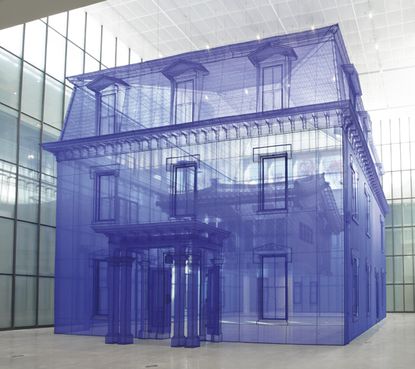 Image of a life-size house with a person stood in the doorway made from translucent fabric in blue