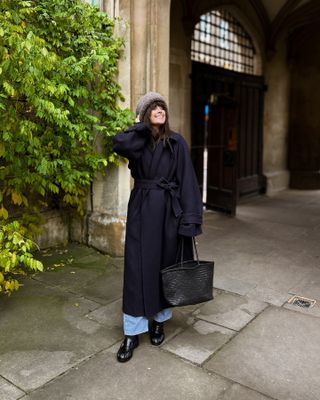 woman wearing a navy coat with jeans and a beanie hat