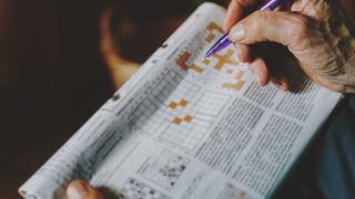 senior man completing a crossword in a newspaper