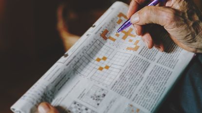 senior man completing a crossword in a newspaper