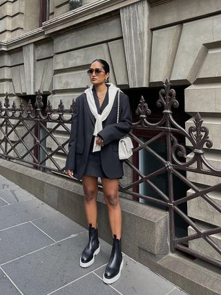 woman wearing gray mini skirt with black mid-calf chelsea boots and matching blazer