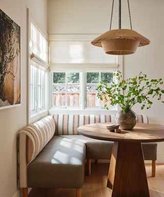 eat-in kitchen with round table and banquette seat with striped cushion