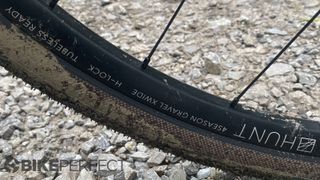 Closeup of Hunt 4 Season Gravel Disc X-Wide wheel with gravel behind