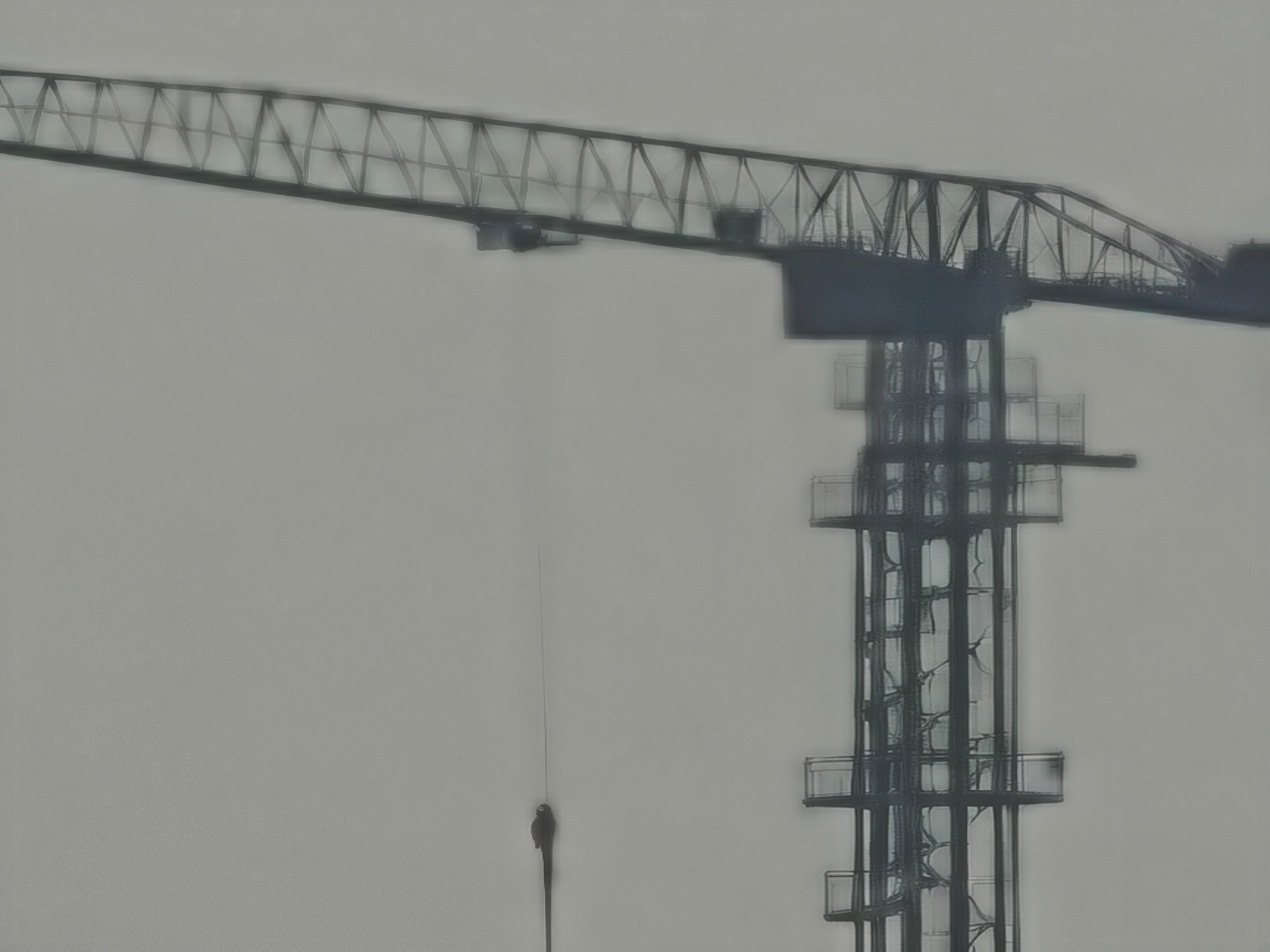 A further extreme digital zoom on the same construction crane. The image is highly processed and blurry, focusing on the junction where the crane's horizontal arm meets the vertical tower. A thin cable hangs down from the arm into the hazy gray void.