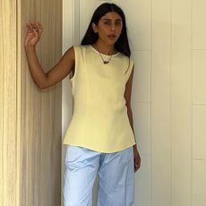 Influencer standing in butter yellow top and light blue pants.