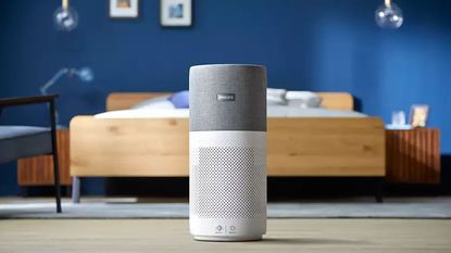 The Philips 3000i Series AC3033/30 Connected Air Purifier in a bedroom with a wooden bed and blue walls