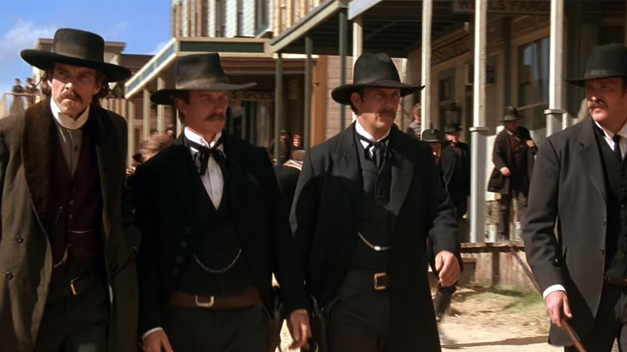 The cast of Wyatt Earp walking in dark suits and dark hats