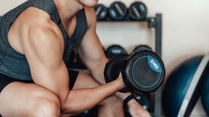 Man lifts a dumbbell and flexes his upper arm