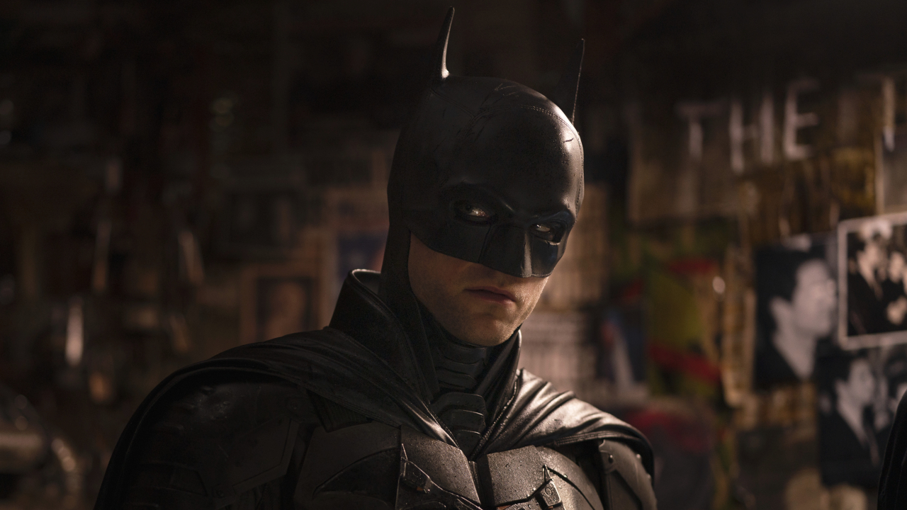 Robert Pattinson casts a sideways glance while standing in The Riddler&#039;s apartment in The Batman. 