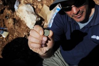 Pablo Betzer, IAA District Archaeologist for Judah, holds a coin from the fourth year of the Great Revolt.