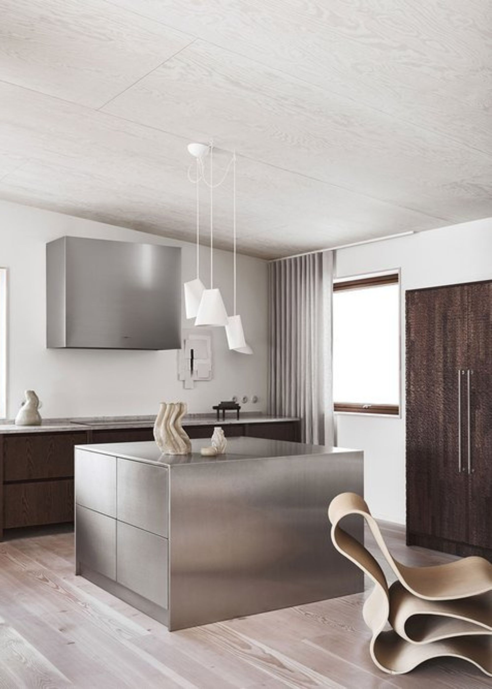 Sleek and modern kitchen with a stainless steel square kitchen island and dark wooden cabinetry