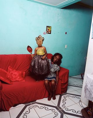 Photography by Deana Lawson, An Ode to Yemaya, 2019, of a woman and child on a red couch