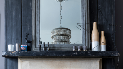 Renovated flat in an Edwardian villa in Surrey, home of Lisa James. Detail of the living room fireplace, traditional marble mantle and mirror, fairy lights star shape and ornaments.