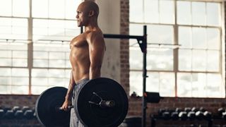 muscular man lifting a barbell off the floor