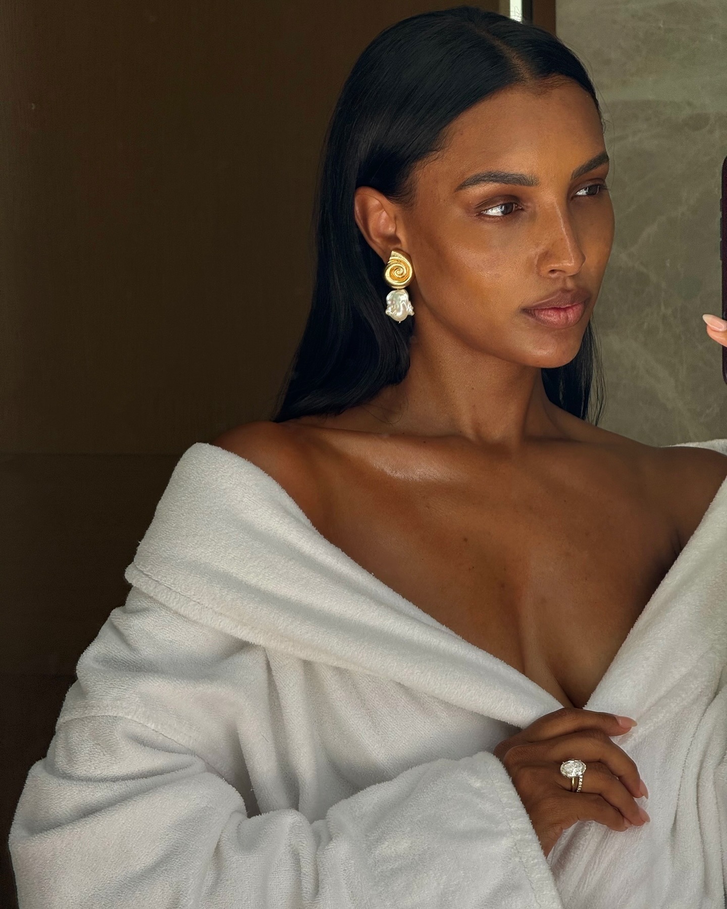 Jasmine Tookes taking a mirror selfie with her hair styled with sleek front pieces tucked behind her ears.