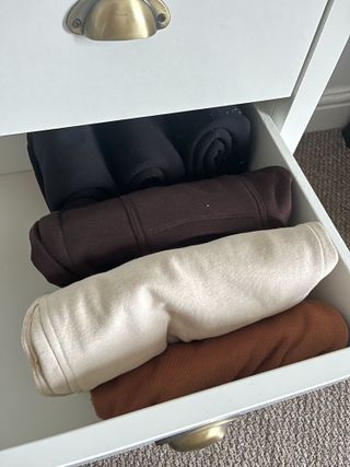 Sweatpants and black leggings file folded in a white dresser drawer