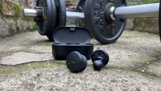 NuraTrue workout earbuds and charging case by dumbbells