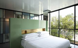 Casa Fayette bedroom with pale green, multifunctional headboards , white bed linen, large windows