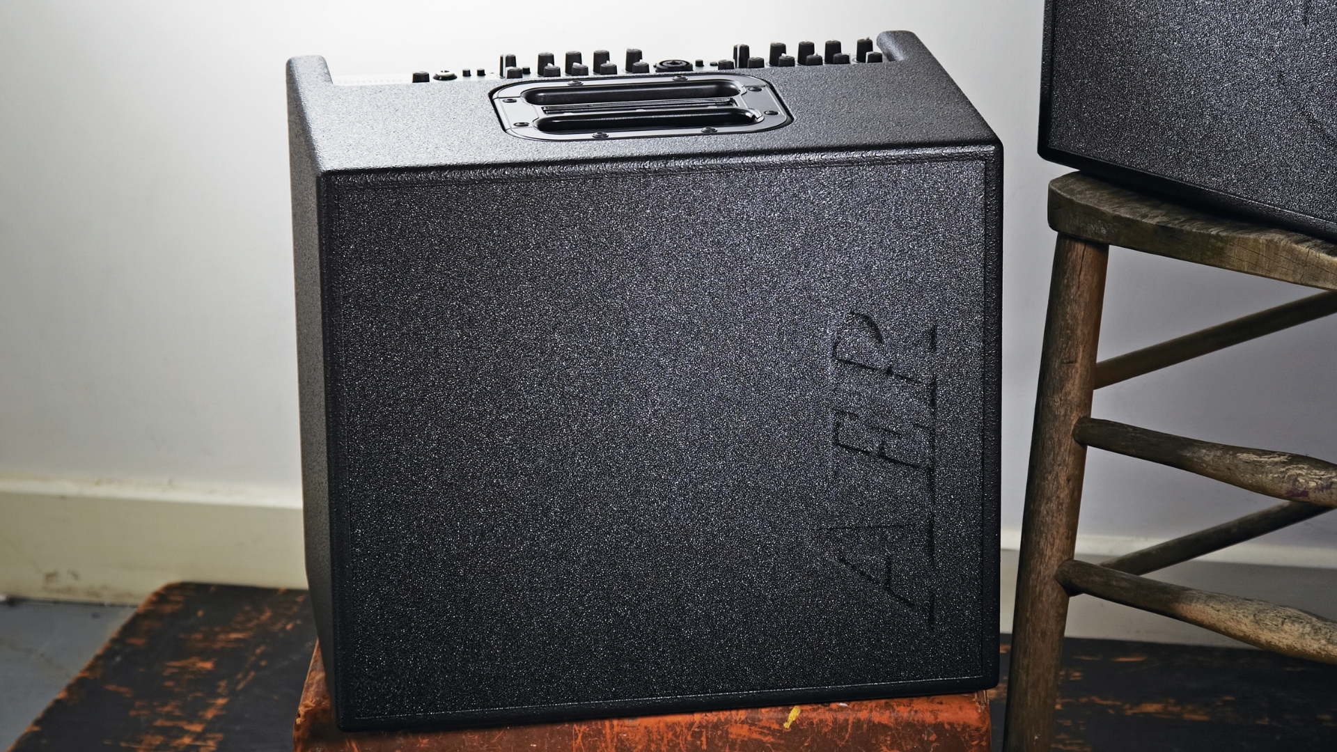 An AER Compact 60 MkIV acoustic guitar amp on a stool