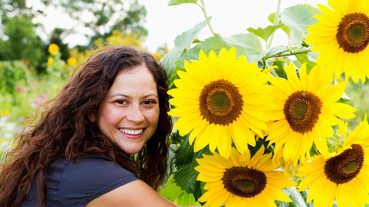 Woman smiling next to sunflowers