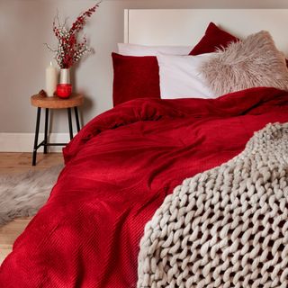 room with red blanket and side table