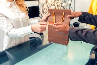 Salesclerk handing merchandise to customer in boutique