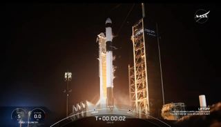 a rocket lifting off at night surrounded by launch towers