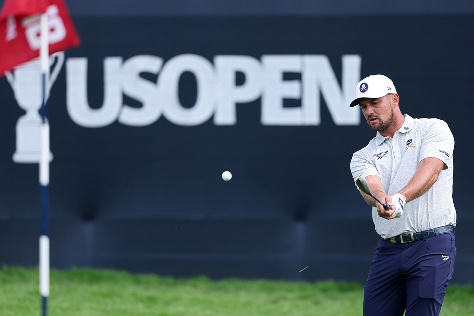 Bryson DeChambeau playing a chip shot in a practice round at the 2025 US Open at Oakmont, where he will be defending his US Open title from 2024