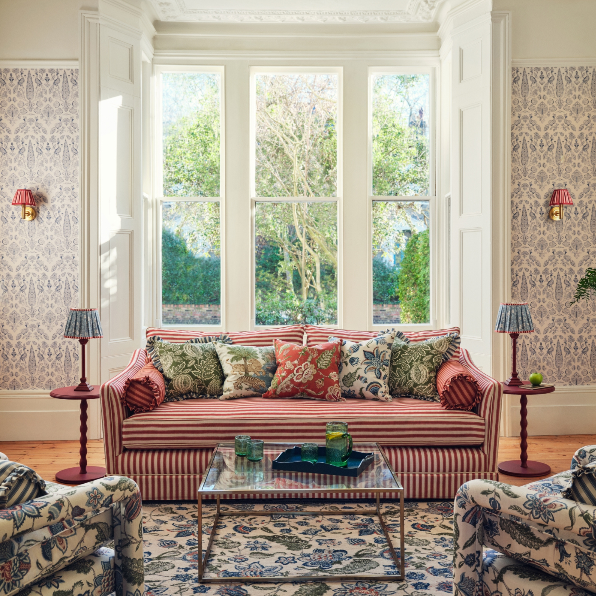 Living room featuring sanderson wallpaper, rugs and red striped sofa.