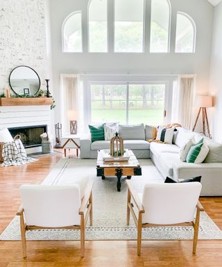 Corner fireplace in white living room with fabric and wooden armchairs, big area rug and coffee table