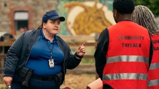 Diane wearing a PCSO uniform points angrily at two community payback workers.