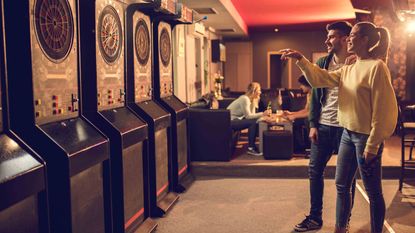 Man and woman playing darts at an arcade