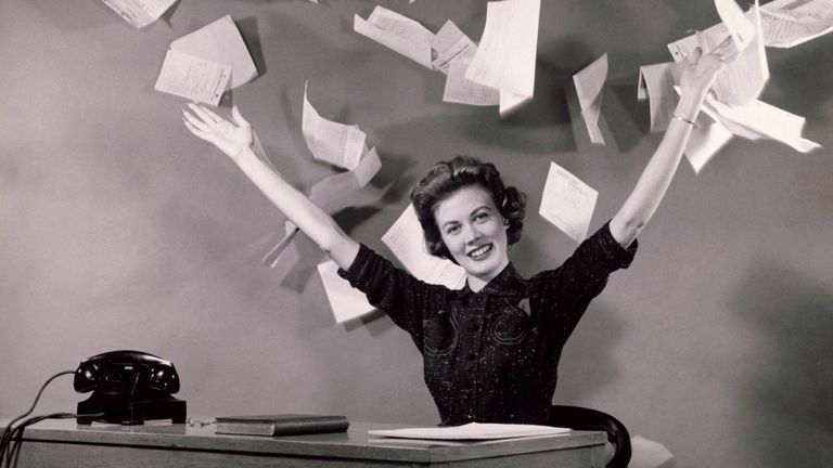 Woman at desk topping papers in air