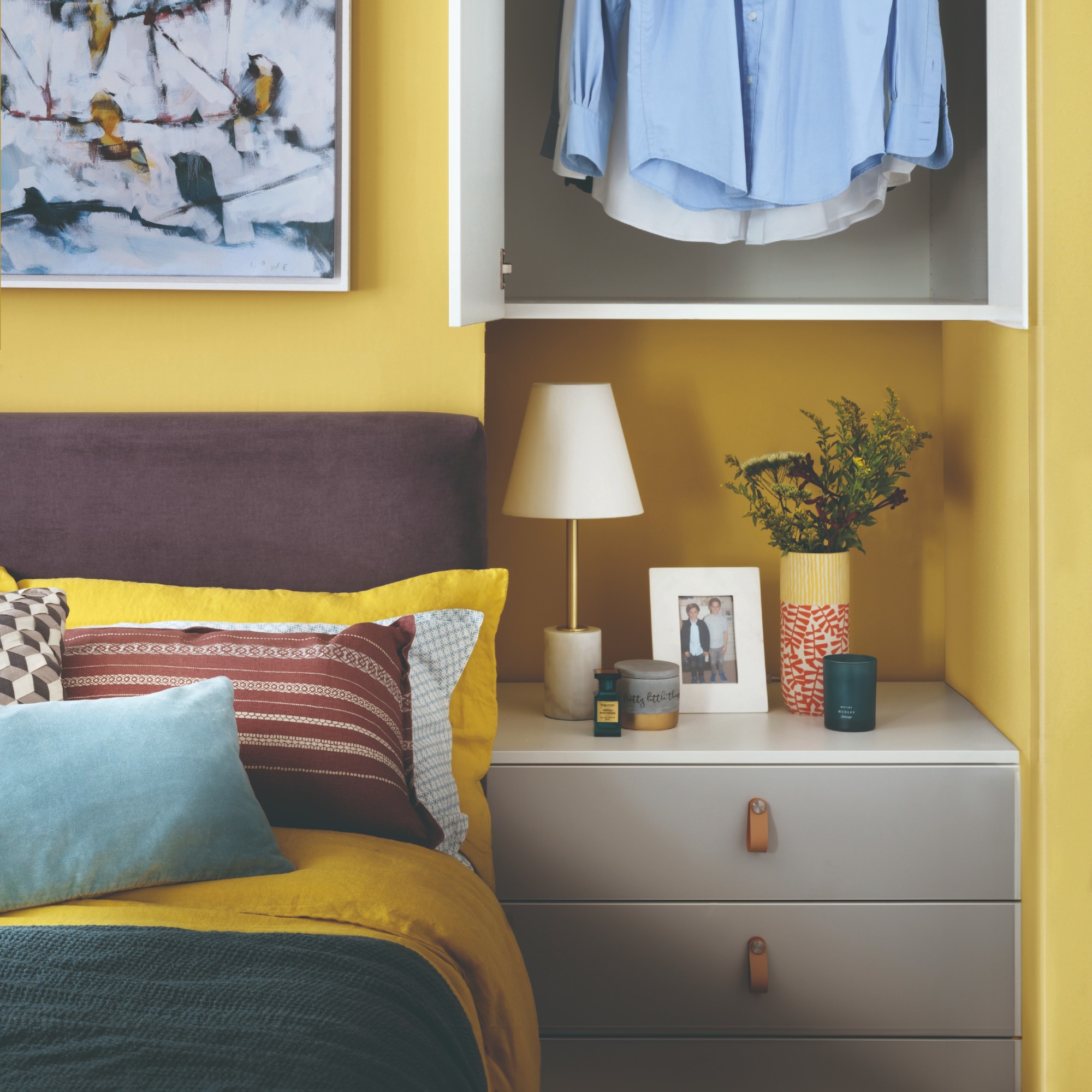 A yellow-painted bedroom with an aubergine-toned headboard