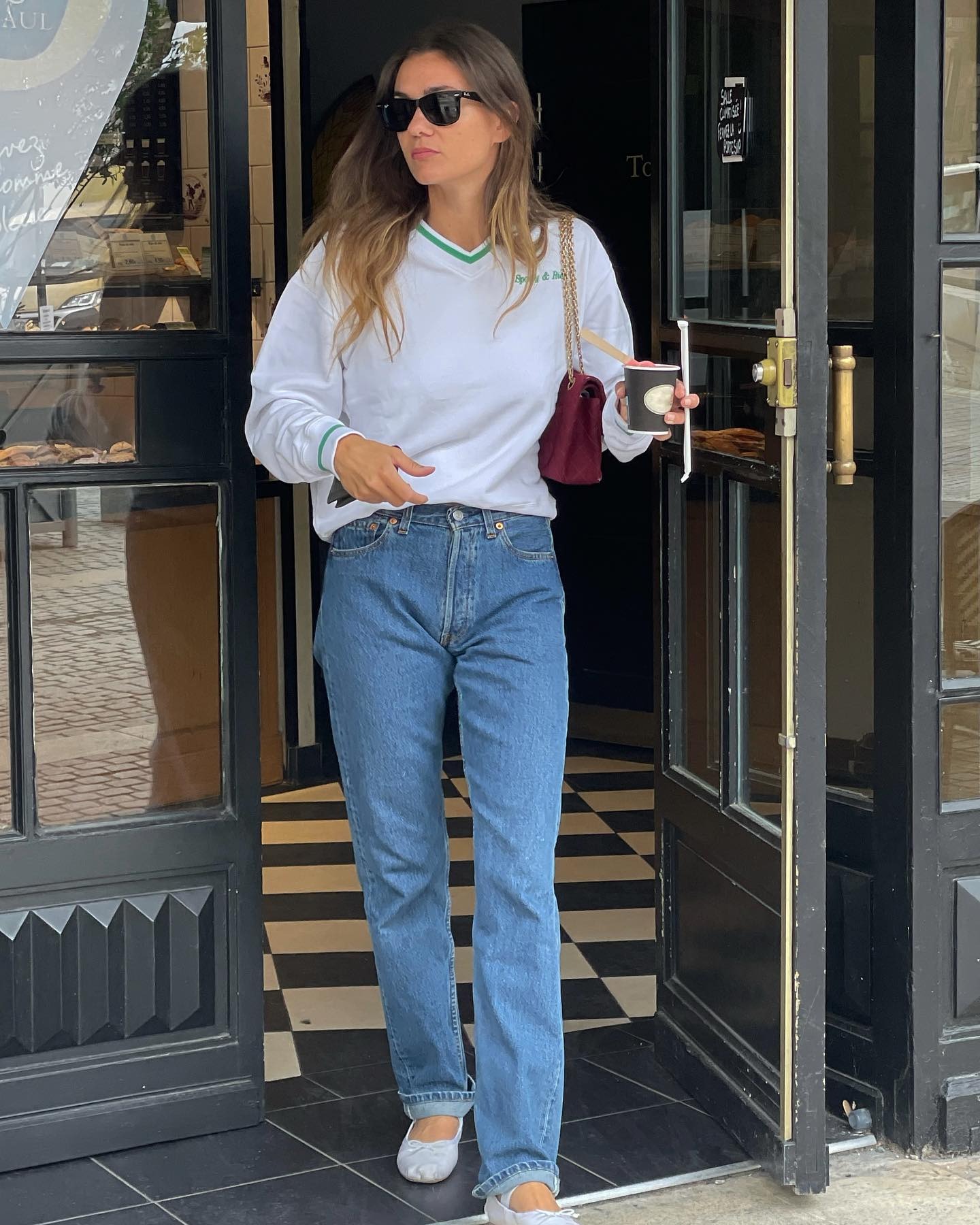 French influencer @annelauremais wears white ballet flats with blue high-waisted jeans and a white long-sleeve top.