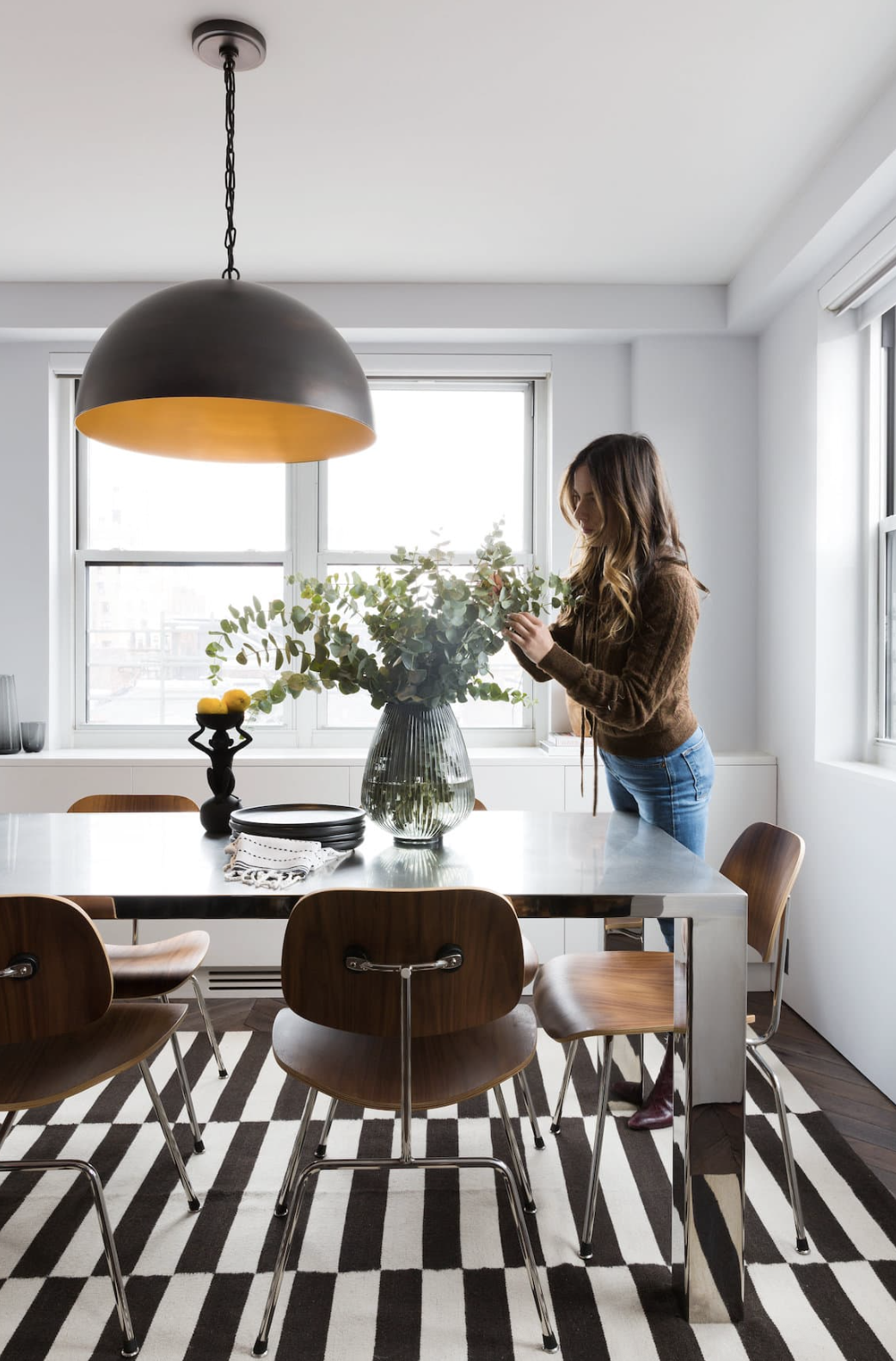 Marina Hanisch leaning over a dining table arranging eucalyptus in a vase