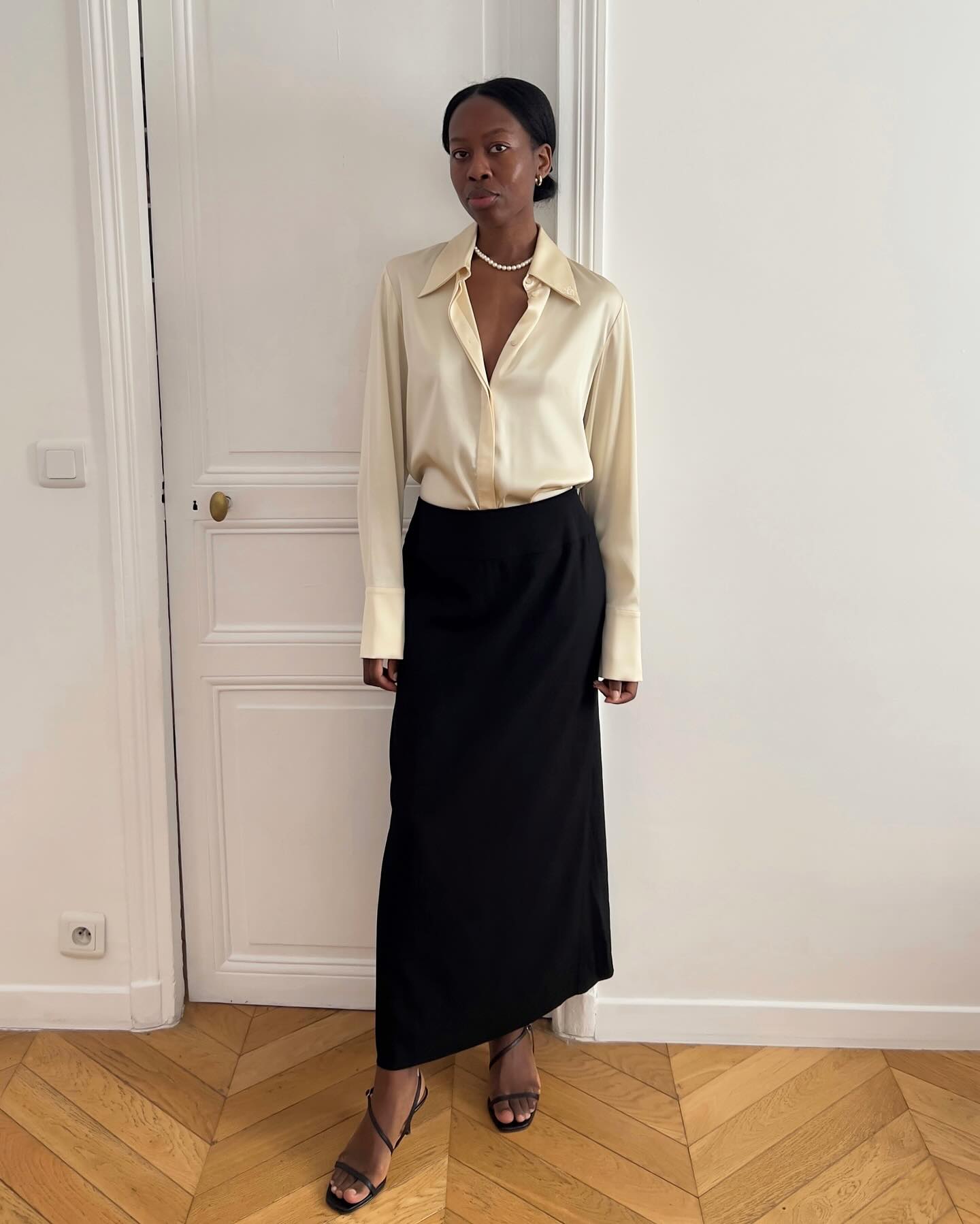 Woman wearing a silk button down and black maxi skirt.