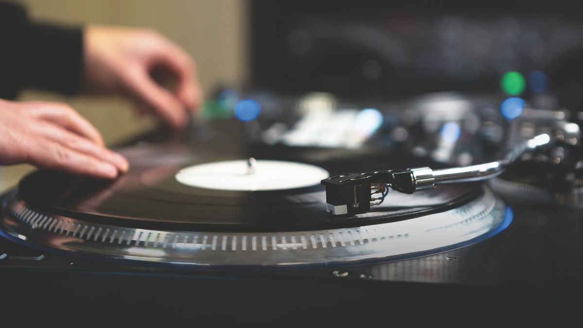 A man uses vinyl on a pair of DJ turntables