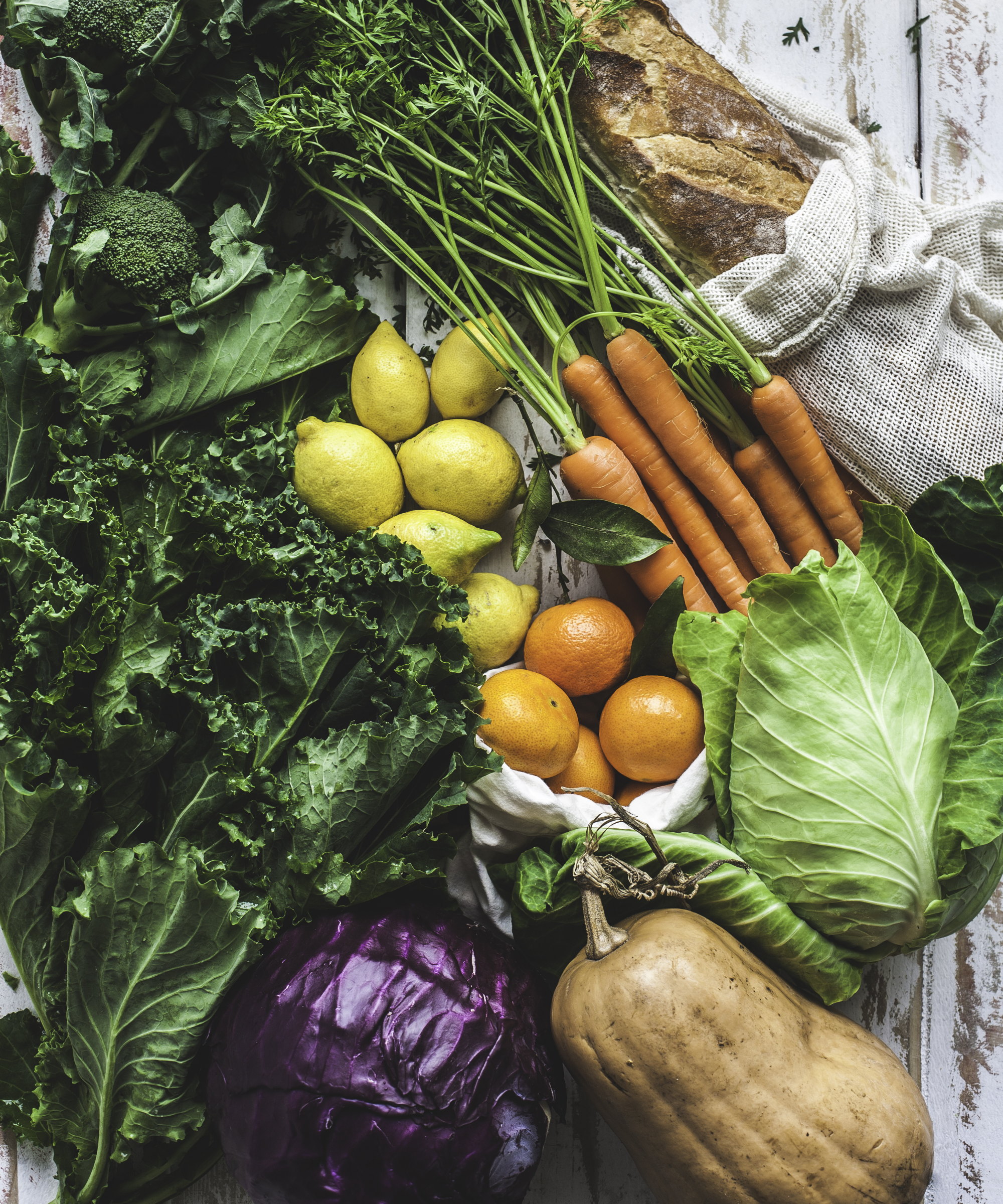 Fresh vegetables such as cabbage, kale, carrots, broccoli, and squash on a wooden table
