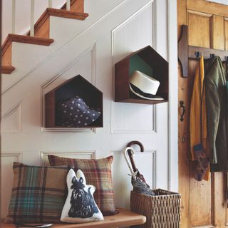 A hallway with floating shelves, a bench and hooks on the back of a door