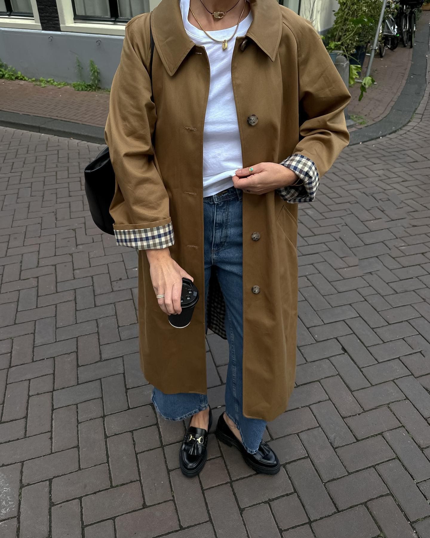 Francesca wears trench coat, straight jeans and loafers
