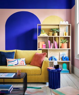 colorful living room with yellow sofa, wall paint effects mural, bookshelf with colorful home accessories - Habitat