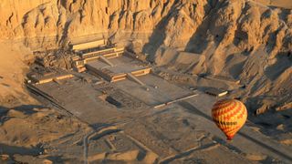 : In an aerial view, a hot air balloon flies over the mortuary temple of Hatshepsut along the West Bank on February 2, 2023 in Luxor, Egypt.