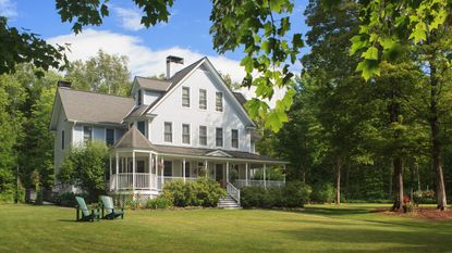 Victorian home with lawn and large front porch in summer