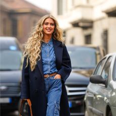 woman with big curly hair walks down the street smiling - gettyimages 1469088128