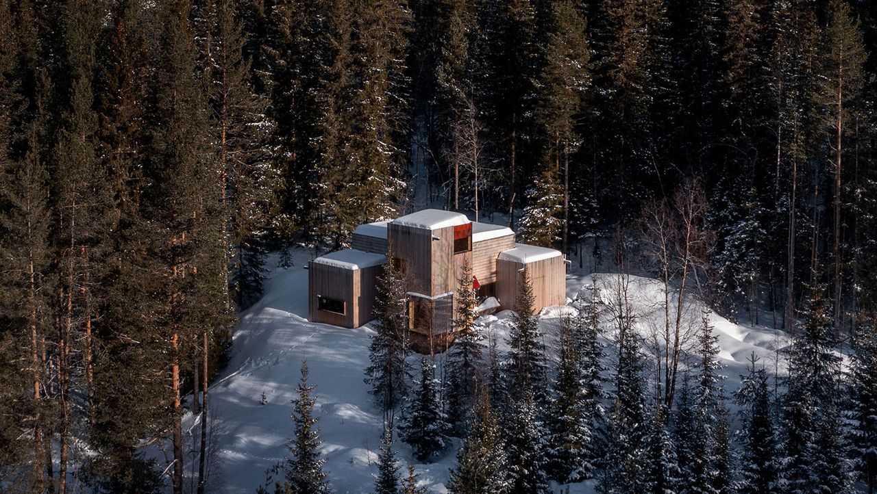 Gartnerfuglen&#039;s Aarestua cabin hero exterior from air among snowy forest