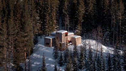 Gartnerfuglen's Aarestua cabin hero exterior from air among snowy forest