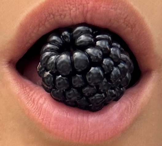 An image of a woman with a blackberry in her mouth.